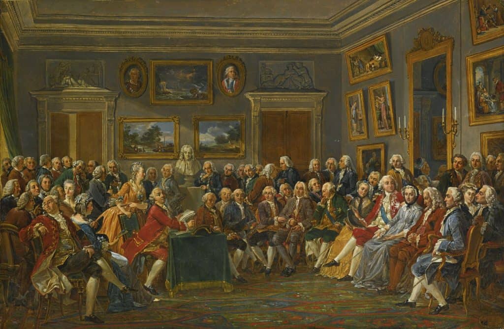 A painting shows people gathered around one reading Voltaire.